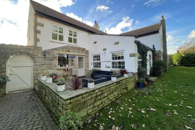 The appealing family home has a lawned garden with a walled patio seating area.