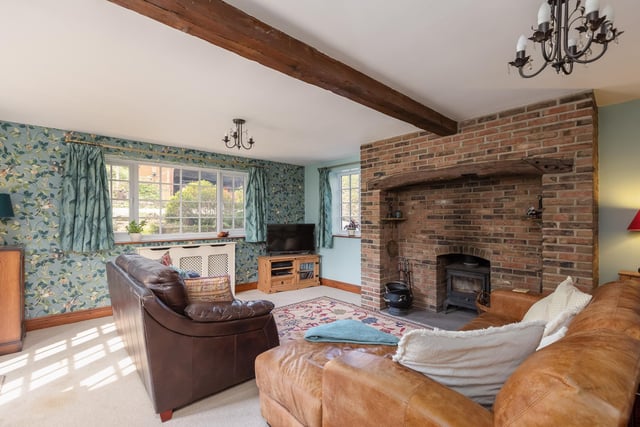 A rustic style beamed living room, with feature brick fireplace and cosy wood burning stove.
