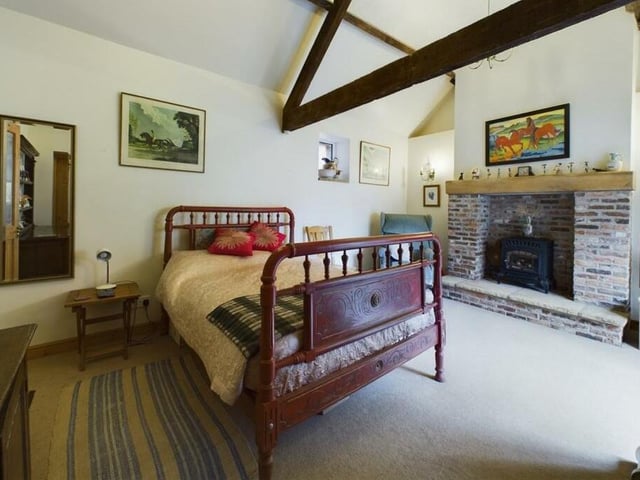 A beamed room with rustic fireplace and stove.