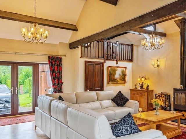 A stunning reception room with beamed ceiling and log burner.