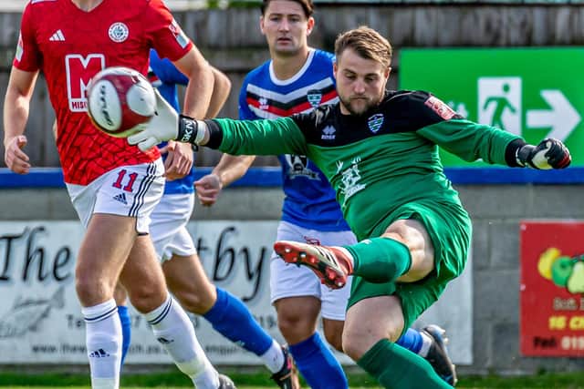 Whitby keeper Shane Bland boots the ball clear.