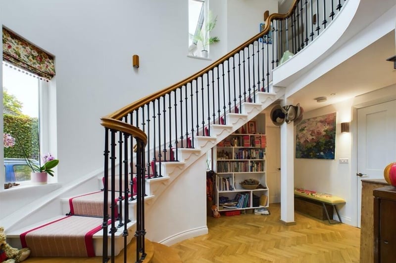 The grand staircase with iron balustrade rises to the gallery landing from the hallway.