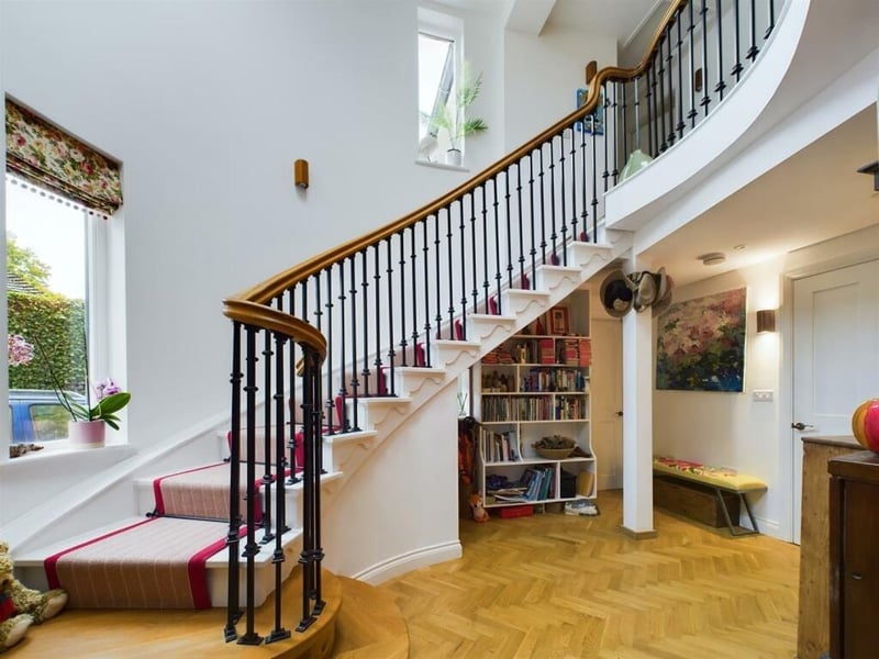The grand staircase with iron balustrade rises to the gallery landing from the hallway.