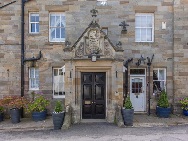 The grand entrance doorway to the Hall has a stone portico with carvings including a motto and crest.