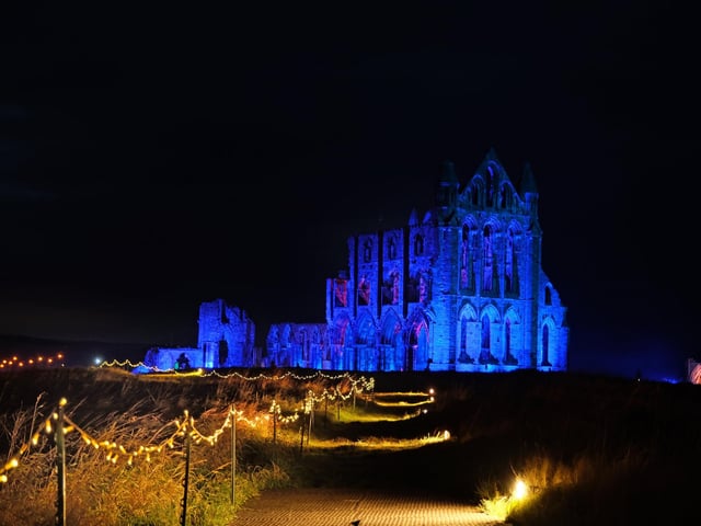 A lit up path leading to a lit up abbey.