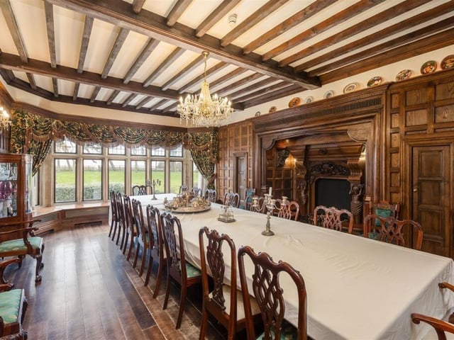 The stunning formal dining room has a wooden carved inglenook fireplace.
