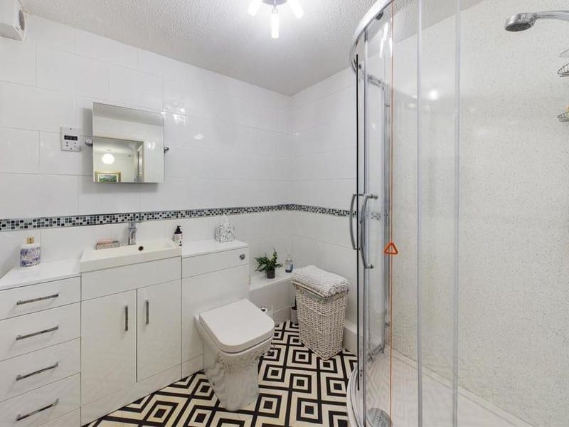 The stylish shower room with vanity unit and storage.
