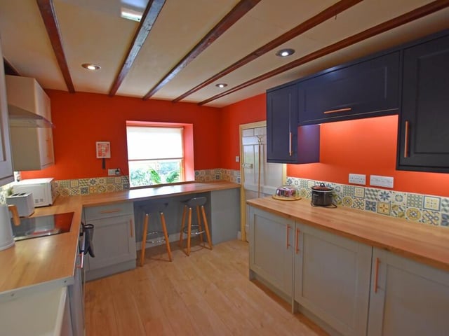 A bright and modern kitchen has fitted units and breakfast bar.