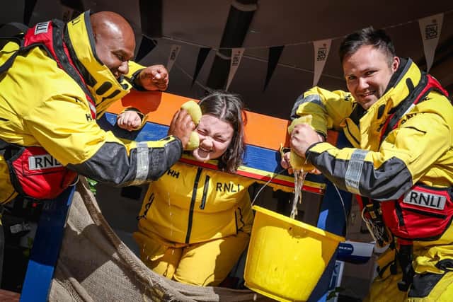 Crew members Ali Hussein and Niall Fagan soak Emily Clarkson in the Flag weekend Stocks. Photo courtesy of RNLI/Ceri Oakes.