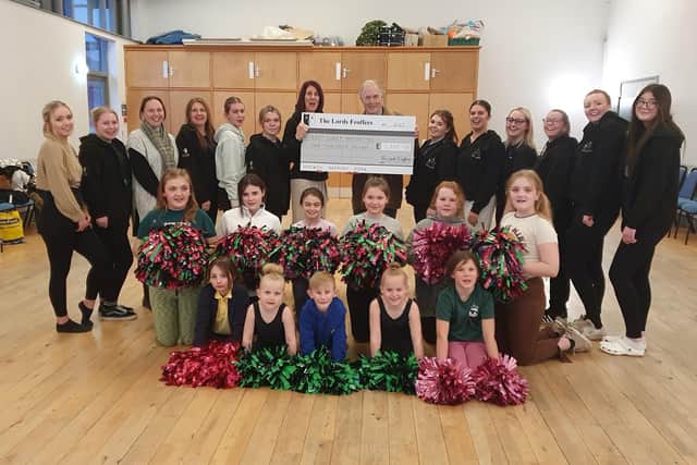 Lord Feoffee Dr. Allan J. S. Watson pictured holding the £1000 cheque with Julie Kirkham, team Secretary, surrounded by some team members.