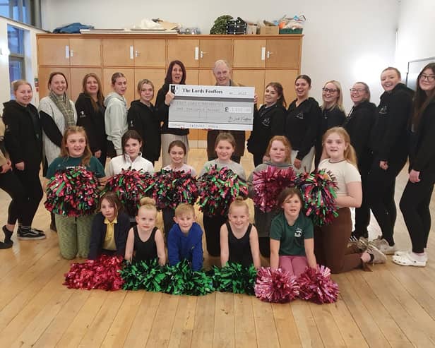 Lord Feoffee Dr. Allan J. S. Watson pictured holding the £1000 cheque with Julie Kirkham, team Secretary, surrounded by some team members.