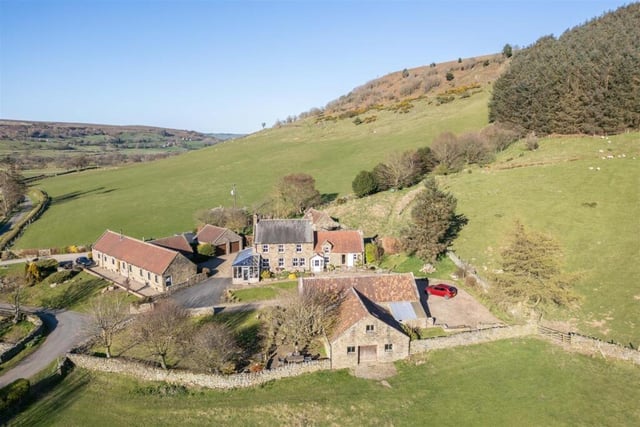 An overview of the unusual hillside farmstead that has its land reing fenced, with a beck dividing its grassland to the south.