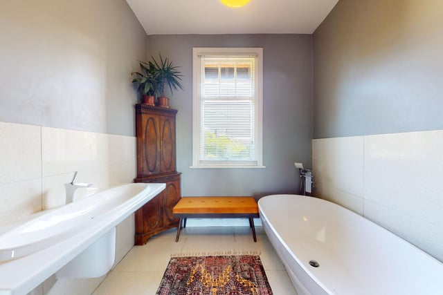 A free standing bath and matching wash basin form part of the suite within this well lit bathroom.