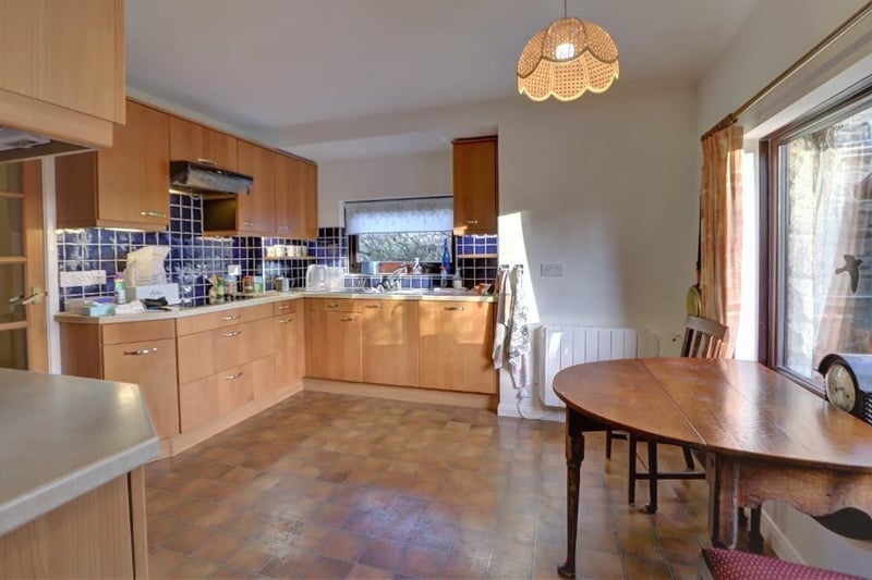 The spacious dining kitchen, with fitted units and integrated appliances, looks over the garden with pond.