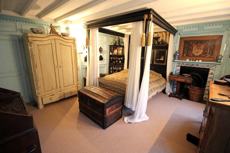 A stunning bedroom with fireplace and panelled walls.