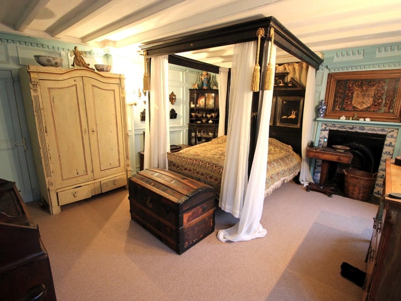 A stunning bedroom with fireplace and panelled walls.
