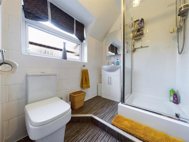 A modern shower room with wash basin set within a vanity unit.