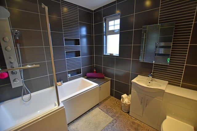A modern, tiled bathroom with washbasin vanity unit.