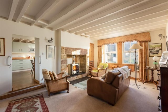 The beamed sitting room with a charming window seat has a cosy log burner.
