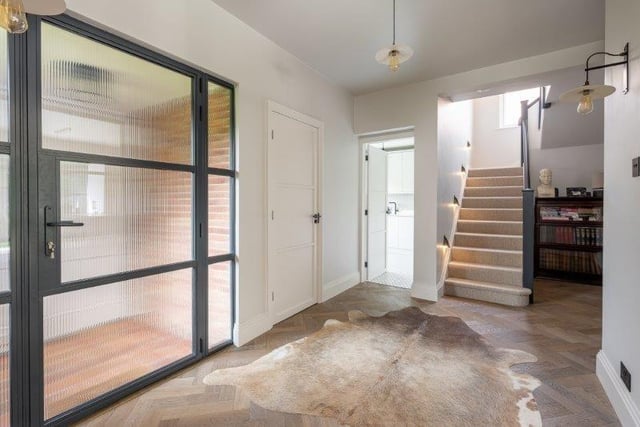 The spacious hallway has engineered oak herringbone flooring, fitted shelving and designer stair lights.