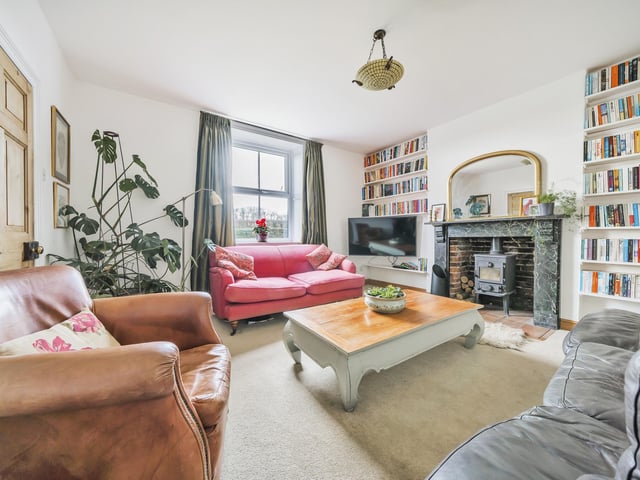 A farmhouse reception room with central fireplace and woodburning stove.