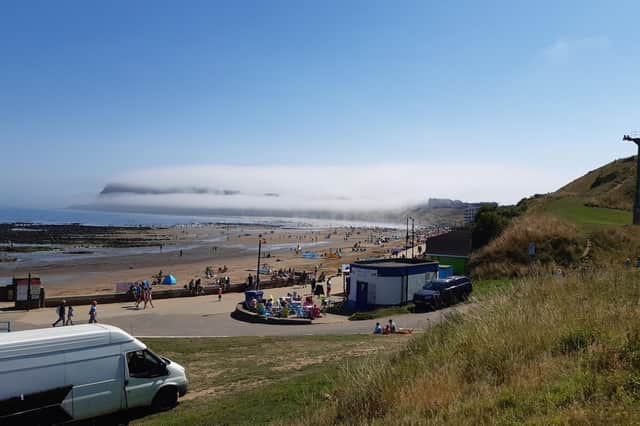 Scarborough castle and headland shrouded in sea fret while North Bay beach basks in sunshine on Saturday