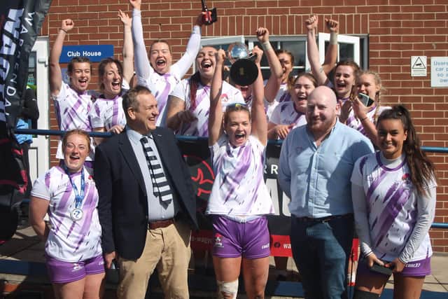 Manchester Metrodogs lift the Amy Hardy Cup after receiving it from Pocklington RUFC President Paul Rhodes (left) and Warrendale Wagyu director James Thornton (right).