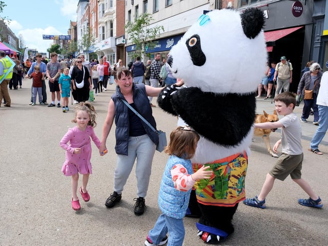 A  giant fluffy panda amusing crowds of people on the busy streets!