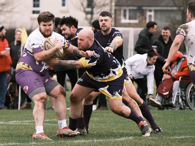 A Pirates player looks to hold off the attentions of Old Boys tacklers