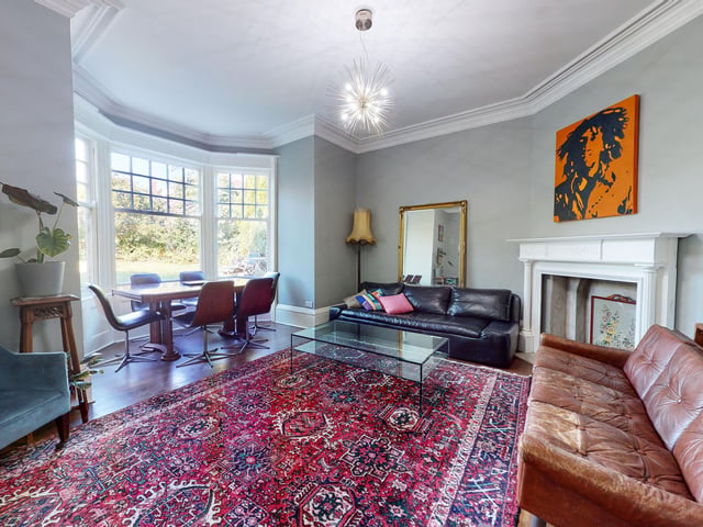 A central fireplace and a large bay window allowing natural light to pour in are features of these open plan rooms.