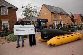 Rio handing the cheque to Chris from British Divers Marine Life Rescue next to the charity's rescue equipment