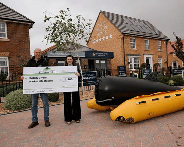 Rio handing the cheque to Chris from British Divers Marine Life Rescue next to the charity's rescue equipment