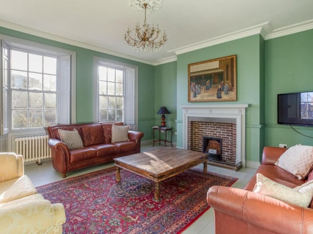 A reception room with large Georgian style windows, and a central feature fireplace.
