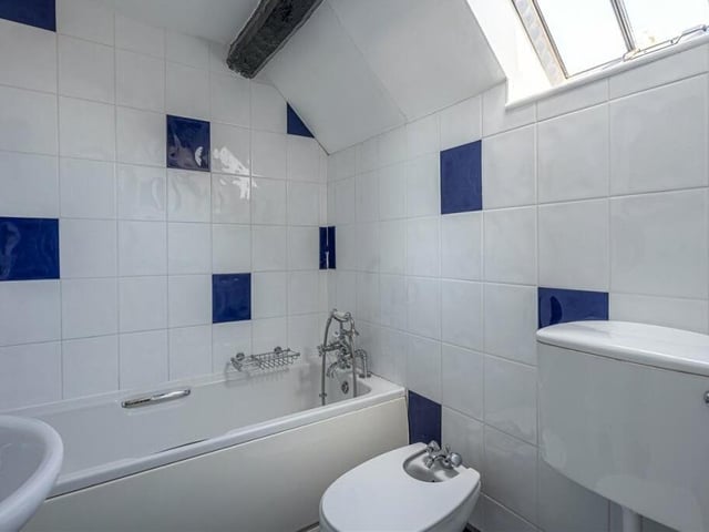 A bathroom with skylight window and beamed ceiling.