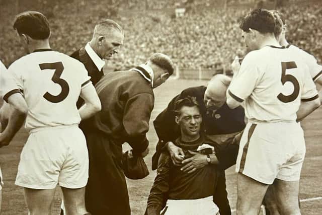 Training staff help the injured Manchester United keeper Ray Wood - referee Frank Coultas is second left.