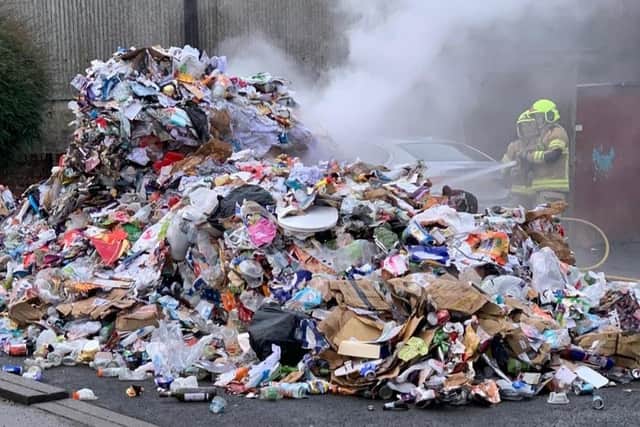 Firefighters douse the smouldering recycling waste from the bin lorry.