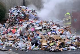 Firefighters douse the smouldering recycling waste from the bin lorry.