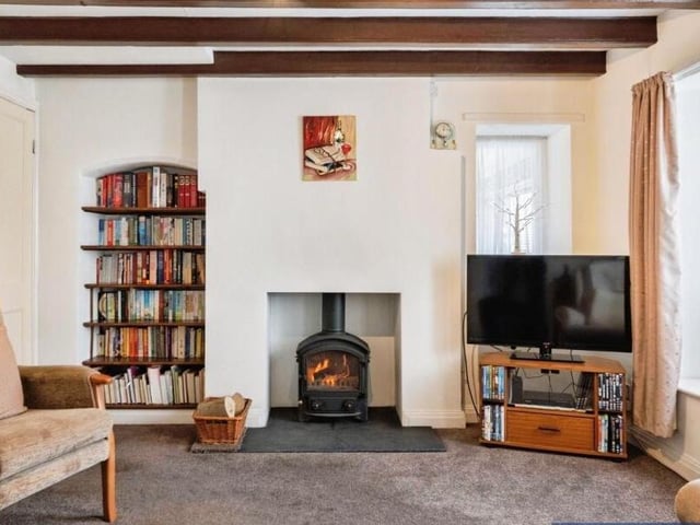 A beamed reception room with alcoves and stove.