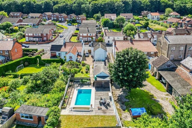 An aerial view of the property with pool, gardens, and outbuildings.