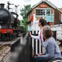 Man and woman at Grosmont Station, watching a heritage train pass.