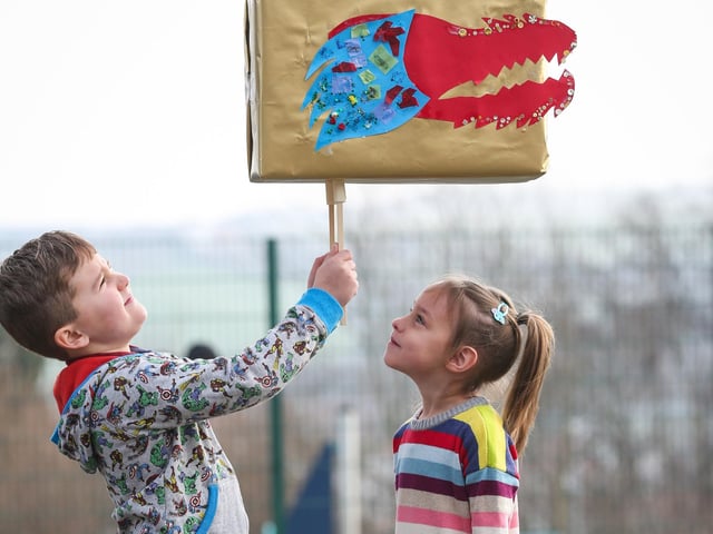 Children from Airy Hill Primary School hold aloft a dragon's head they created for the Chinese New Year.