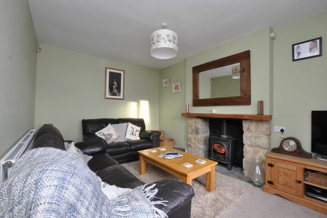 A cosy sitting room with stone fireplace and warming stove.
