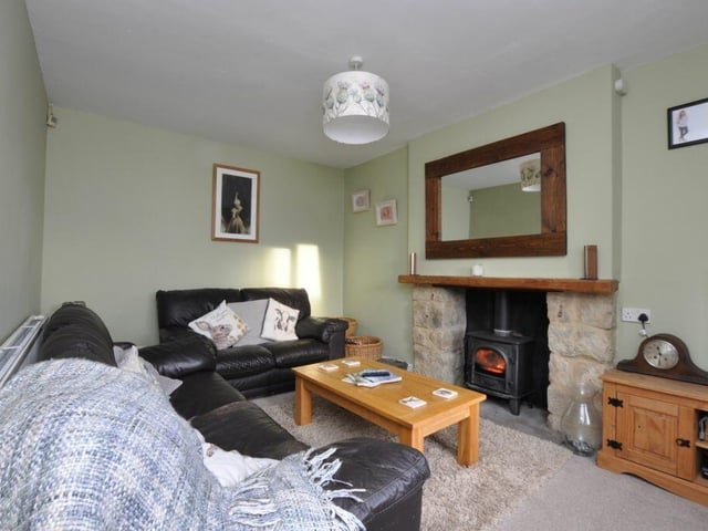 A cosy sitting room with stone fireplace and warming stove.