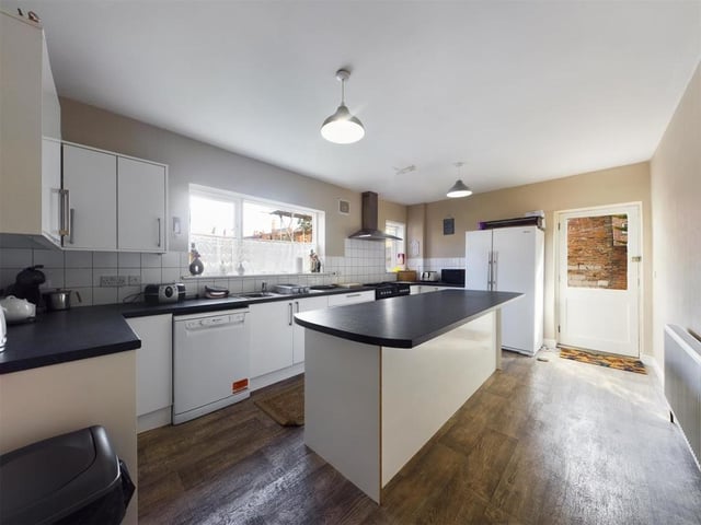 A modern fitted kitchen has a central island and includes a Flavel free standing oven with gas hob and stainless steel extractor fan.