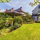 A rear view of the property from its colourful gardens with deep-filled borders and seating areas.