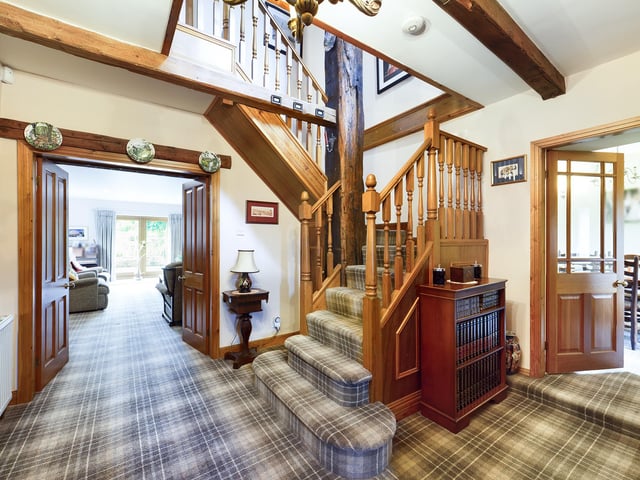 The carpeted hallway with ceiling beams opens through to ground floor rooms.