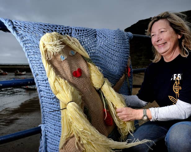 Jacqueline Power arranges the knitted Mermaid on the seafront in Staithes