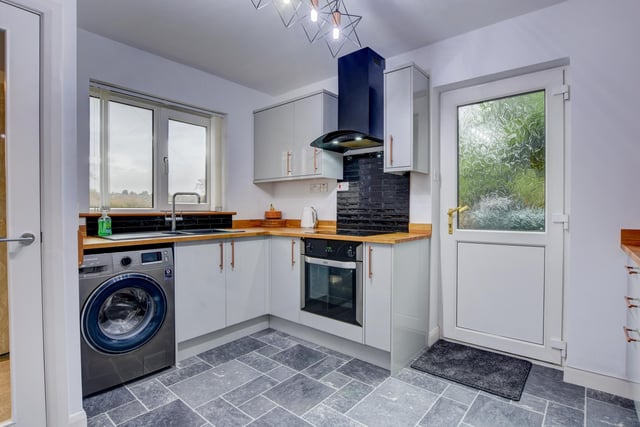 The kitchen, with fitted units , oak worktops and built-in appliances, has windows with a view, and a door leading outside.