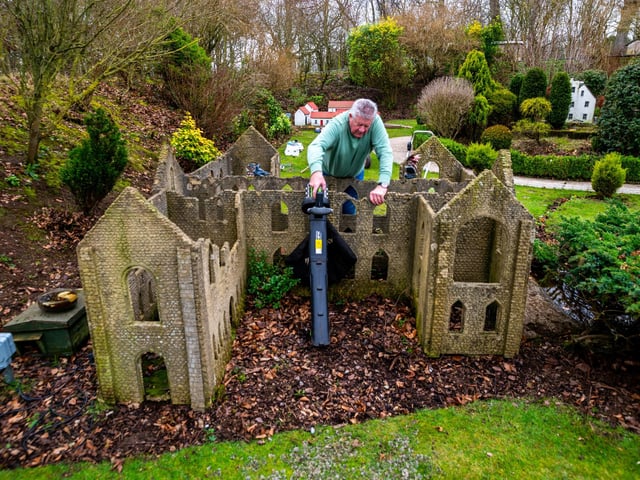 John Kenny, clearing leaves from the St Valentine Abbey model within the village