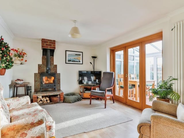 A sitting room, with feature fireplace and stove, opens through to a conservatory.